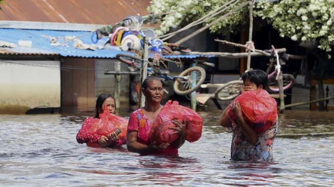 Sejumlah warga membawa bungkusan sembako saat melintasi permukiman masyarakat di tepian Sungai Kapuas, Sintang, Kalimantan Barat, Kamis (18/11/2021). [ANTARA FOTO/Jessica Helena Wuysang]