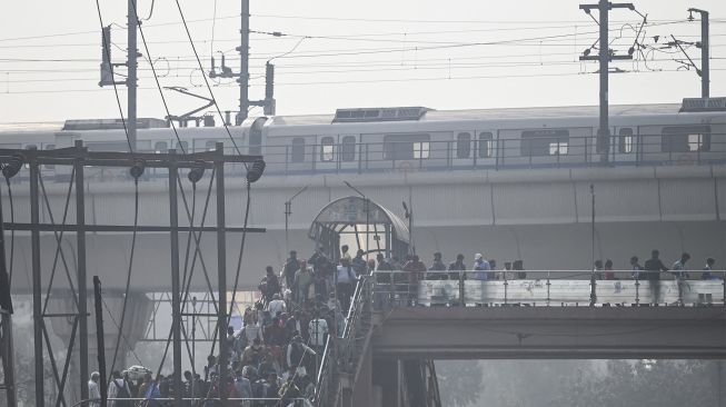 Pejalan kaki berjalan di atas jembatan saat kabut asap tebal di New Delhi, India, pada (16/11/2021). [MONEY SHARMA / AFP]