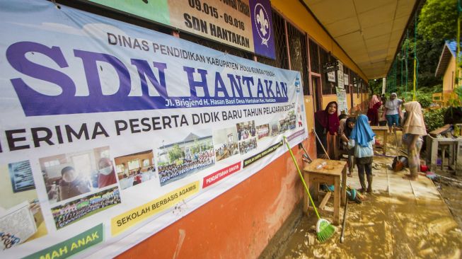 Sejumlah murid membersihkan ruang kelas SD Negeri Hantakan dari lumpur akibat meluapnya sungai Hantakan di Kecamatan Hantakan, Kabupaten Hulu Sungai Tengah, Kalimantan Selatan, Jumat (19/11/2021). [ANTARA FOTO/Bayu Pratama S]