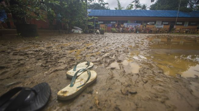 Sejumlah murid membersihkan ruang kelas SD Negeri Hantakan dari lumpur akibat meluapnya sungai Hantakan di Kecamatan Hantakan, Kabupaten Hulu Sungai Tengah, Kalimantan Selatan, Jumat (19/11/2021). [ANTARA FOTO/Bayu Pratama S]