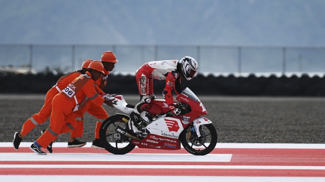 Pembalap Thailand Watcharin Tubtimon (kanan) mencoba menyalakan motornya dengan dibantu marshall usai insiden tabrakan saat balapan kelas Idemitsu Asia Talent Cup (IATC) 2021 di Pertamina Mandalika International Street Circuit, Lombok Tengah, Nusa Tenggara Barat, Jumat (19/11/2021). [ANTARA FOTO/Andika Wahyu]