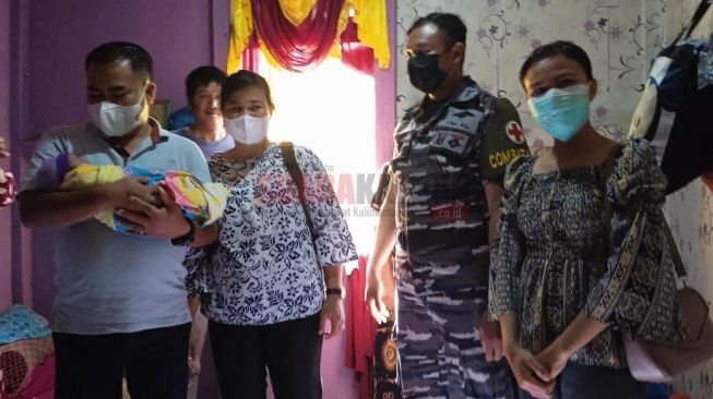 Bupati Sekadau Aron didampingi istrinya Magdalena Susilawati Aron,memberikan bantuan berupa paket perlengkapan bayi kepada warga terdampak banjir asal Dusun Teribang, Kecamatan Sekadau Hilir, Kabupaten Sekadau yang melahirkan di atas perahu karet TNI AL, Sabtu (20/11/2021) siang. [SUARAKALBAR.CO.ID/ Bernadetha Firnanda]