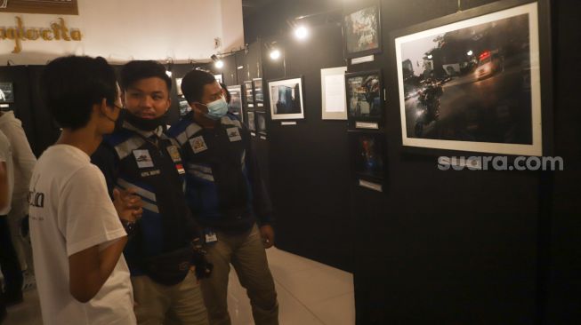 Sejumlah pengunjung melihat foto-foto yang ditampilkan pada pameran foto 'Anglocita' di Depok, Jawa Barat, Minggu (21/11/2021). [Suara.com/Alfian Winanto]