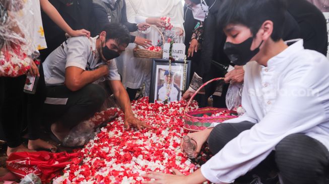 Keluarga berdoa diatas pusara mantan Atlet Bulutangkis Hj. Verawaty Fajrin usai dimakamkan di TPU Tanah Kusir, Jakarta Selatan, Minggu (21/11/2021). [Suara.com/Alfian Winanto]