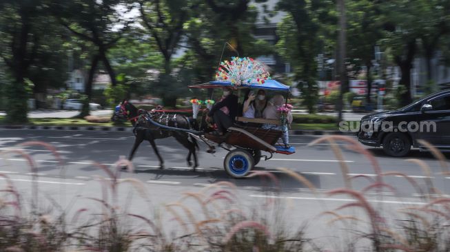 Warga berwisata dengan delman di Kawasan IRTI Monas, Jakarta Pusat, Minggu (21/11/2021). [Suara.com/Alfian Winanto]