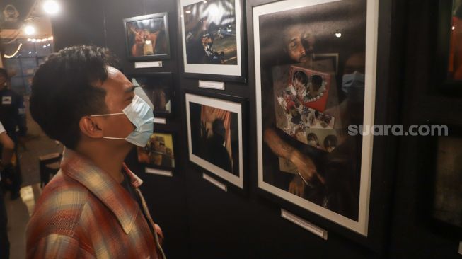 Sejumlah pengunjung melihat foto-foto yang ditampilkan pada pameran foto 'Anglocita' di Depok, Jawa Barat, Minggu (21/11/2021). [Suara.com/Alfian Winanto]