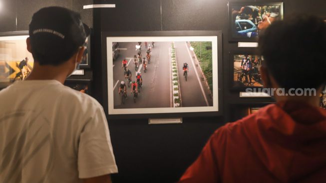 Sejumlah pengunjung melihat foto-foto yang ditampilkan pada pameran foto 'Anglocita' di Depok, Jawa Barat, Minggu (21/11/2021). [Suara.com/Alfian Winanto]