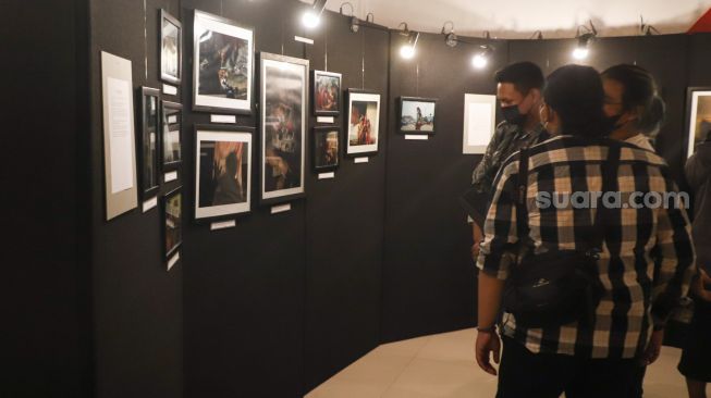 Sejumlah pengunjung melihat foto-foto yang ditampilkan pada pameran foto 'Anglocita' di Depok, Jawa Barat, Minggu (21/11/2021). [Suara.com/Alfian Winanto]