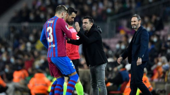 Pelatih Barcelona Xavi (kanan) berbicara dengan Gerard Pique saat pertandingan Liga Spanyol lawan Espanyol di Camp Nou pada 21 November 2021. ANTARA/AFP/PAU BARRENA