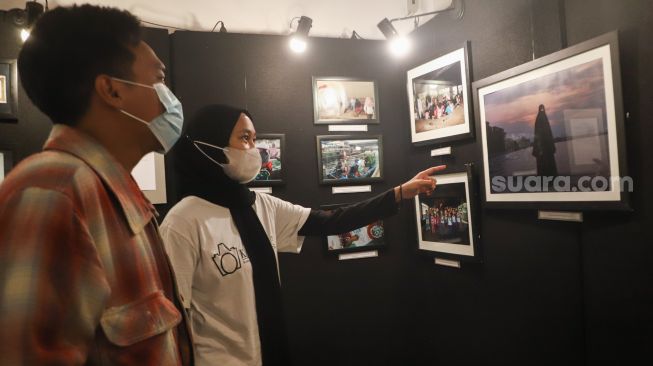 Sejumlah pengunjung melihat foto-foto yang ditampilkan pada pameran foto 'Anglocita' di Depok, Jawa Barat, Minggu (21/11/2021). [Suara.com/Alfian Winanto]