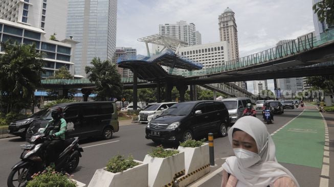 Sejumlah kendaraan melintas di dekat proyek revitalisasi Jembatan Penyeberangan Orang (JPO) Sudirman di Jakarta, Selasa (23/11/2021). [Suara.com/Angga Budhiyanto]