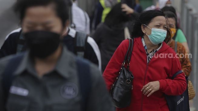 Pekerja berjalan menuju Halte Transjakarta Tosari saat jam pulang kerja di Jakarta, Selasa (23/11/2021). [Suara.com/Angga Budhiyanto]