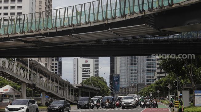 Sejumlah kendaraan melintas di dekat proyek revitalisasi Jembatan Penyeberangan Orang (JPO) Sudirman di Jakarta, Selasa (23/11/2021). [Suara.com/Angga Budhiyanto]