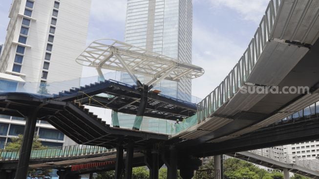 Pekerja menyelesaikan revitalisasi Jembatan Penyeberangan Orang (JPO) Sudirman di Jakarta, Selasa (23/11/2021). [Suara.com/Angga Budhiyanto]