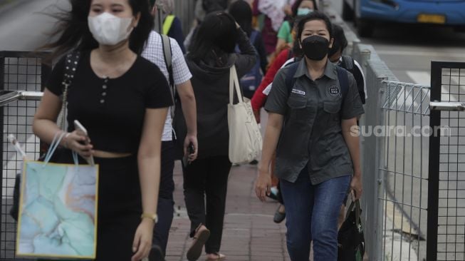 Pekerja berjalan menuju Halte Transjakarta Tosari saat jam pulang kerja di Jakarta, Selasa (23/11/2021). [Suara.com/Angga Budhiyanto]