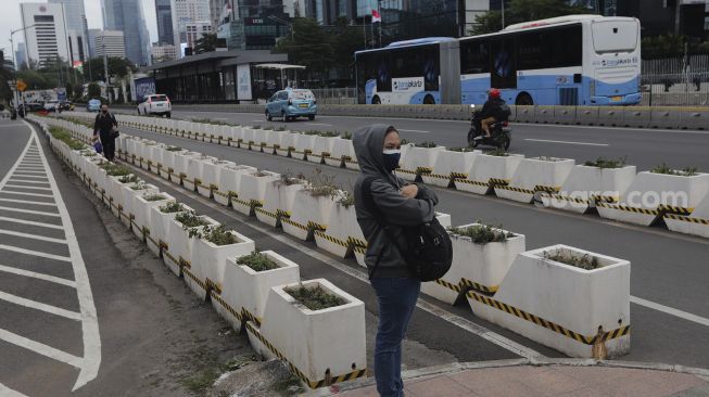 Pekerja menunggu untuk menyeberang di 'pelican cross' Tosari saat jam pulang kerja di Jakarta, Selasa (23/11/2021). [Suara.com/Angga Budhiyanto]