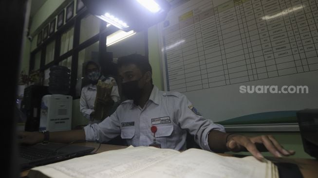 Petugas Dinas Perpustakaan dan Kearsipan (Dispusip) Provinsi DKI Jakarta mendigitalisasikan arsip sekolah di SMAN 77, Cempaka Putih, Jakarta, Rabu (24/11/2021). [Suara.com/Angga Budhiyanto]