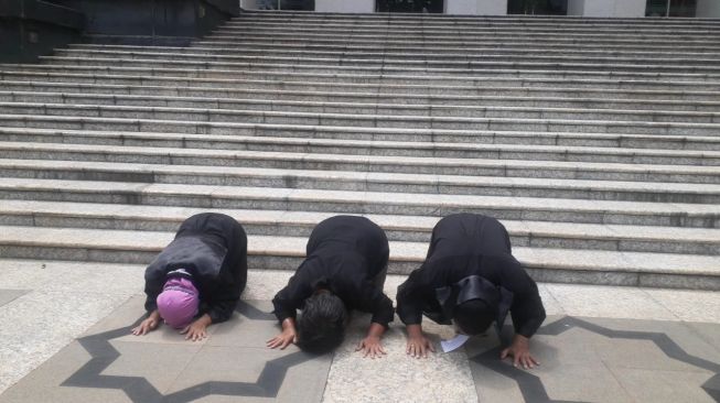 Penggugat UU Cipta Kerja melakukan sujud syukur usai mengikuti sidang di Mahkamah Konstitusi pada Kamis (25/11/2021). [Suara.com/Yaumal]