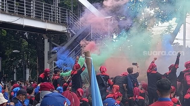 Massa buruh saat menyaksikan sidang putusan uji materi UU Ciptaker secara daring di lokasi demonstrasi di kawasan Patung Kuda, Jakarta Pusat. (Suara.com/Yosea Arga)