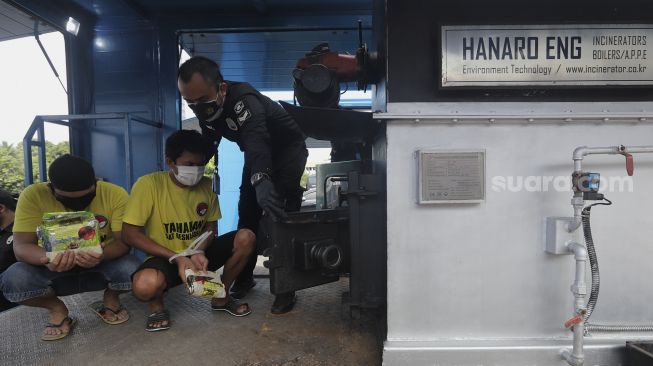 Tersangka memasukkan barang bukti narkoba ke dalam mesin pemusnah di Mapolda Metro Jaya, Jakarta, Kamis (25/11/2021). [Suara.com/Angga Budhiyanto] 