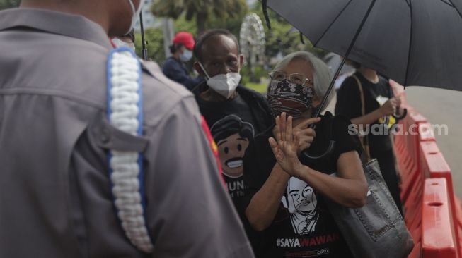 Ibunda korban tragedi semanggi I BR Norma Irmawan, Maria Katarina Sumarsih berdiskusi dengan polisi saat mengikuti aksi Kamisan di depan Istana Merdeka, Jakarta, Kamis (25/11/2021). [Suara.com/Angga Budhiyanto]