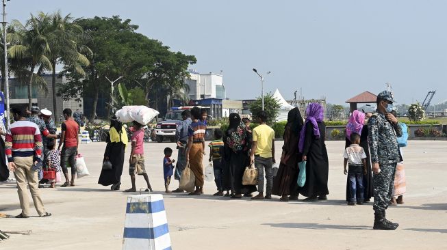 Pengungsi Rohingya berjalan dalam antrian saat mereka turun dari bus untuk dipindahkan ke pulau Bhashan Char di Teluk Benggala, Chittagong Boat Club, Chittagong, pada (25/11/2021). [MUNIR UZ ZAMAN / AFP]