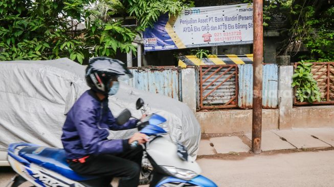 Pengendara sepeda motor melintas di depan rumah milik terpidana korupsi Eddy Tansil di Petogogan, Jakarta Selatan, Minggu (28/11/2021).[Suara.com/Alfian Winanto]