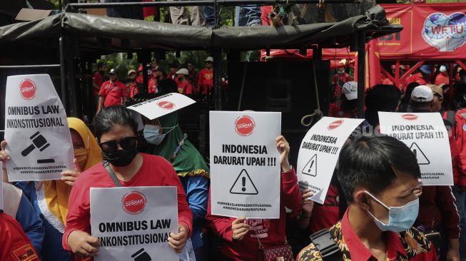 Sejumlah buruh membawa poster saat menggelar aksi unjuk rasa menolak upah minimum provinsi (UMP) di depan Balai Kota DKI Jakarta, Senin (29/11/2021). [Suara.com/Angga Budhiyanto]