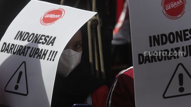 Buruh menghadirkan poster pada waktu menyelenggarakan aksi unjuk rasa menolak upah minimum provinsi (UMP) di tempat depan Balai Pusat Kota DKI Jakarta, Mulai Pekan (29/11/2021). [Suara.com/Angga Budhiyanto]