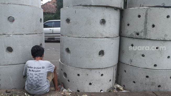 Warga beraktivitas di dekat buis beton drainase vertikal di kawasan Manggarai, Jakarta Selatan, Selasa (30/11/2021). [Suara.com/Alfian Winanto]