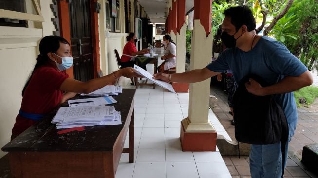 Orang tua siswa mengambil soal Penilaian Akhir Semester (PAS) semester ganjil tahun pelajaran 2021/2022 karena pembelajaran dilaksanakan secara daring menyusul adanya kasus COVID-19 di SD Negeri 11 Pemecutan, Denpasar, Bali, Selasa (30/11/2021).  ANTARA FOTO/Nyoman Hendra Wibowo