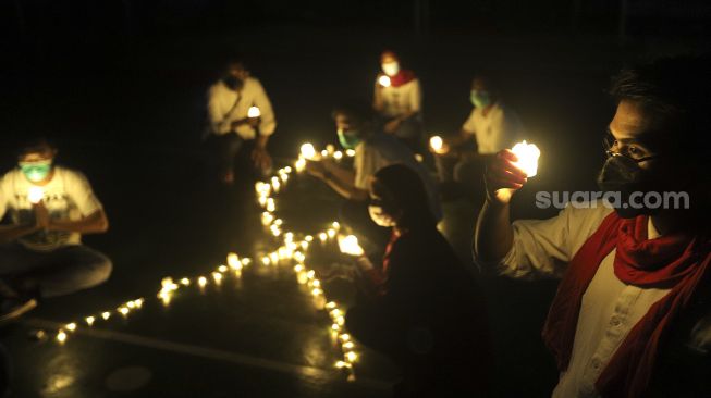 Relawan menyalakan lampu dalam malam renungan Hari AIDS Sedunia di Tanah Abang, Jakarta, Rabu (1/12/2021). [Suara.com/Angga Budhiyanto]