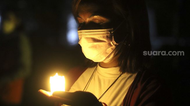 Relawan menyalakan lampu dalam malam renungan Hari AIDS Sedunia di Tanah Abang, Jakarta, Rabu (1/12/2021). [Suara.com/Angga Budhiyanto]