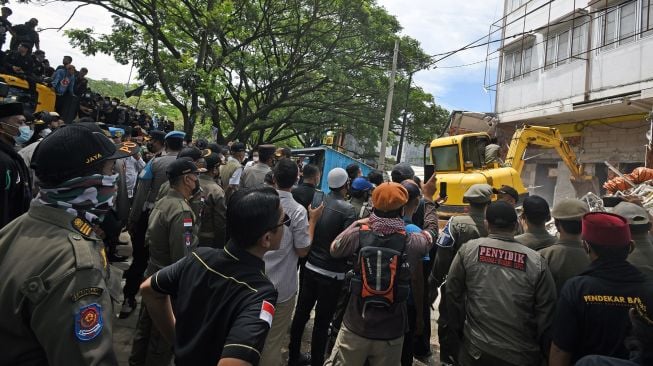 Sejumlah personel Polisi Pamong Praja dengan menggunakan alat berat dan disaksikan ratusan warga membongkar tempat hiburan ilegal di Jalan Lingkar Selatan, Kramatwatu, Serang, Banten, Rabu (1/12/2021).  ANTARA FOTO/Asep Fathulrahman