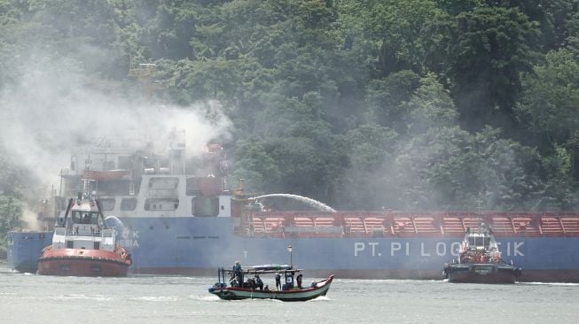 Tim SAR gabungan menggunakan Tugboat melakukan pemadaman kapal kargo Soemantri Brodjonegoro yang terbakar di perairan Teluk Penyu, Cilacap, Jawa Tengah, Rabu (1/12/2021).  ANTARA FOTO/Idhad Zakaria