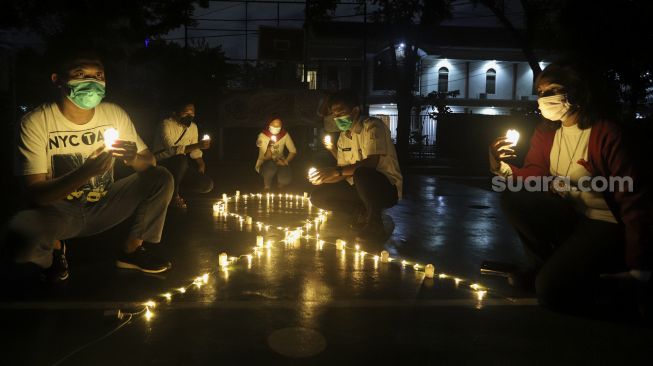 Relawan menyalakan lampu dalam malam renungan Hari AIDS Sedunia di Tanah Abang, Jakarta, Rabu (1/12/2021). [Suara.com/Angga Budhiyanto]