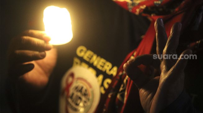 Relawan menyalakan lampu dalam malam renungan Hari AIDS Sedunia di Tanah Abang, Jakarta, Rabu (1/12/2021). [Suara.com/Angga Budhiyanto]