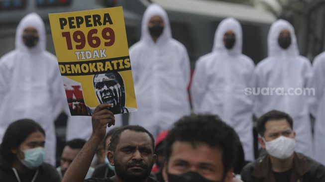 Massa membawa poster saat melakukan aksi unjuk rasa memperingati 60 tahun deklarasi kemerdekaan Papua Barat di kawasan Patung Kuda Arjuna Wiwaha, Jakarta, Rabu (1/12/2021). [Suara.com/Angga Budhiyanto]