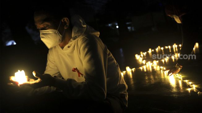 Relawan menyalakan lampu dalam malam renungan Hari AIDS Sedunia di Tanah Abang, Jakarta, Rabu (1/12/2021). [Suara.com/Angga Budhiyanto]