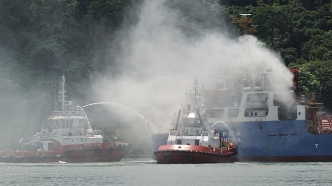 Tim SAR gabungan menggunakan Tugboat melakukan pemadaman kapal kargo Soemantri Brodjonegoro yang terbakar di perairan Teluk Penyu, Cilacap, Jawa Tengah, Rabu (1/12/2021).  ANTARA FOTO/Idhad Zakaria