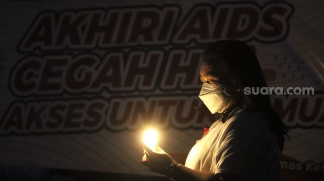 Relawan menyalakan lampu dalam malam renungan Hari AIDS Sedunia di Tanah Abang, Jakarta, Rabu (1/12/2021). [Suara.com/Angga Budhiyanto]