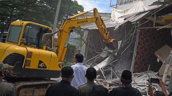 Sejumlah personel Polisi Pamong Praja dengan menggunakan alat berat dan disaksikan ratusan warga membongkar tempat hiburan ilegal di Jalan Lingkar Selatan, Kramatwatu, Serang, Banten, Rabu (1/12/2021).  ANTARA FOTO/Asep Fathulrahman