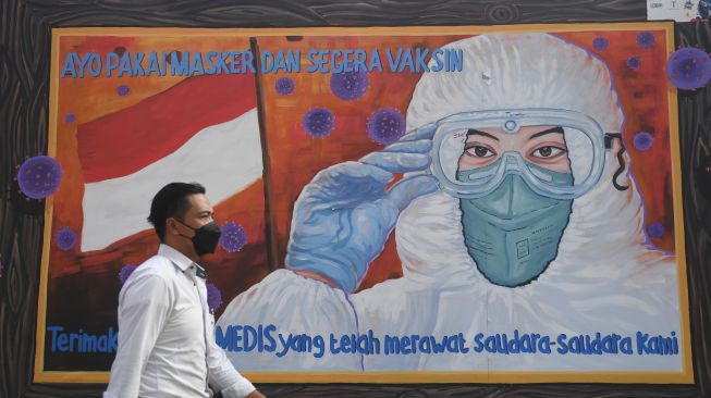 Warga melintas di dekat mural bertema COVID-19 di Jakarta, Rabu (1/12/2021).  ANTARA FOTO/Akbar Nugroho Gumay
