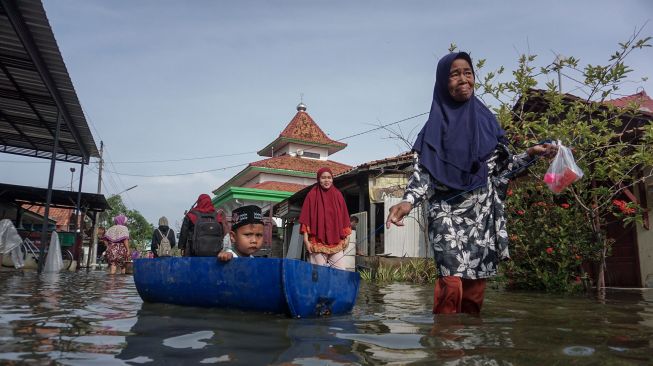 Warga melintas di jalan yang tergenang banjir rob di Degayu, Pekalongan, Jawa Tengah, Kamis (2/12/2021). ANTARA FOTO/Harviyan Perdana Putra