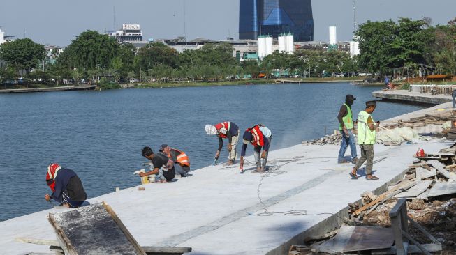 Pekerja menyelesaikan proyek revitalisasi Danau Sunter di Sunter, Jakarta Utara, Kamis (2/12/2021). [Suara.com/Alfian Winanto]