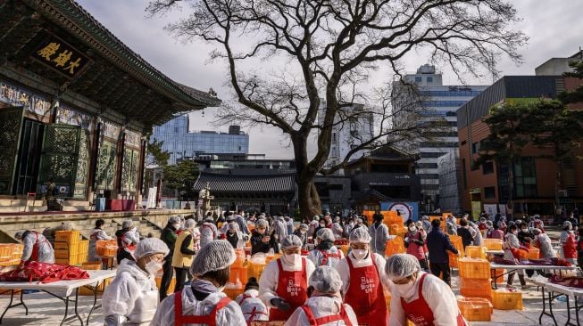 Para peserta menyiapkan kimchi, hidangan tradisional Korea dari kubis dan lobak pedas yang difermentasi, selama festival pembuatan kimchi di kuil Buddha Jogyesa, Seoul, Korea Selatan, pada (2/12/2021). [ANTHONY WALLACE / AFP]