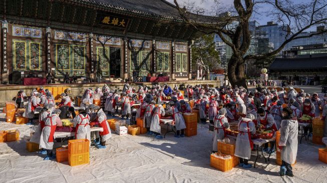 Para peserta menyiapkan kimchi, hidangan tradisional Korea dari kubis dan lobak pedas yang difermentasi, selama festival pembuatan kimchi di kuil Buddha Jogyesa, Seoul, Korea Selatan, pada (2/12/2021). [ANTHONY WALLACE / AFP]