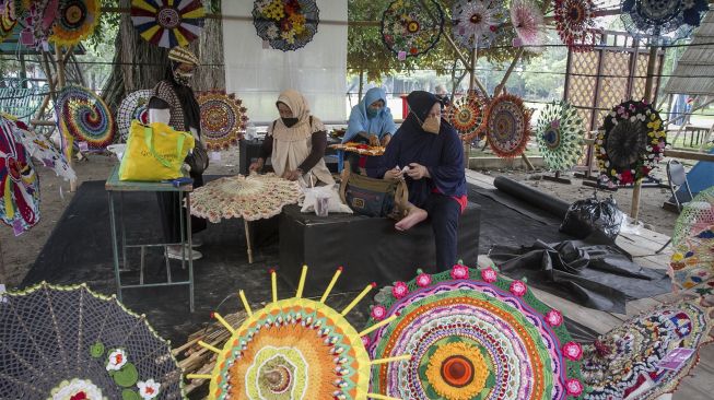 Pengrajin membuat payung rajut pada Festival Payung 2021 di Taman Balekambang, Solo, Jawa Tengah, Jumat (3/12/2021). [ANTARA FOTO/Mohammad Ayudha]