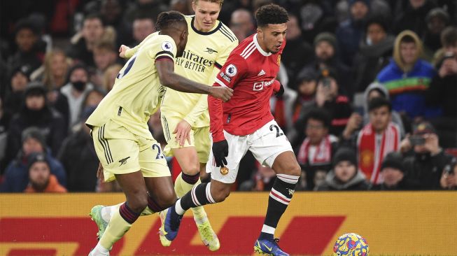 Striker Manchester United Jadon Sancho (kanan) bersaing dengan pemain tengah Arsenal Martin Odegaard (tengah) dan pemain belakang Arsenal Nuno Tavares (kiri) selama pertandingan sepak bola Liga Premier Inggris antara Manchester United dan Arsenal di Old Trafford, Manchester, Inggris, pada (2/12/2021). [OLI SCARFF / AFP]