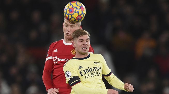 Gelandang Manchester United Scott McTominay (kiri) bersaing dengan gelandang Arsenal Emile Smith Rowe (kanan) selama pertandingan sepak bola Liga Premier Inggris antara Manchester United dan Arsenal di Old Trafford, Manchester, Inggris, pada (2/12/2021). [OLI SCARFF / AFP]